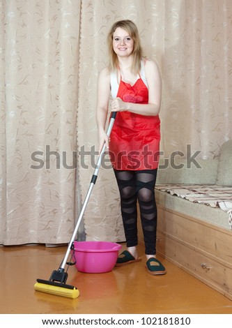 woman washes the floor with mop in the living room