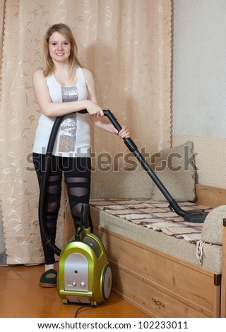 Woman cleans with vacuum cleaner in living room