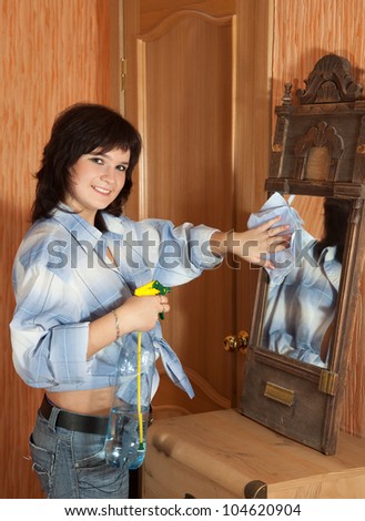 Happy brunette girl cleans mirror indoor