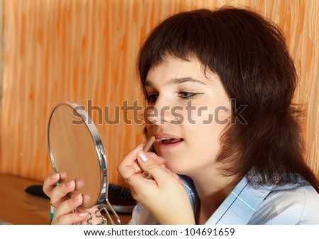 Brunette girl paints lips with pencil in home