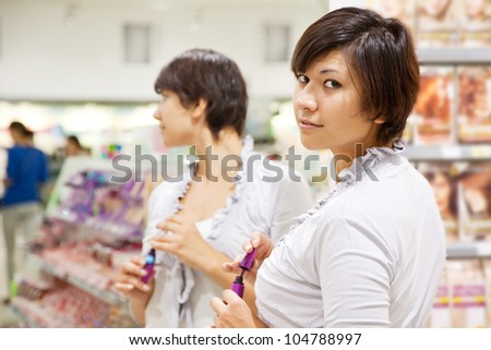 young woman testing the mascara at cosmetics  shop