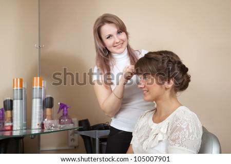 Female hair stylist working with long-haired girl. Focus on customer