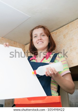 Woman glues ceiling tile at home