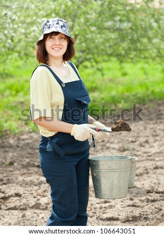 Female gardener fertilizes the soil in garden