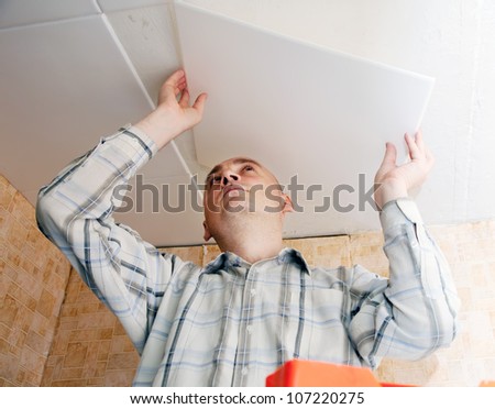 Man glues ceiling tile at home