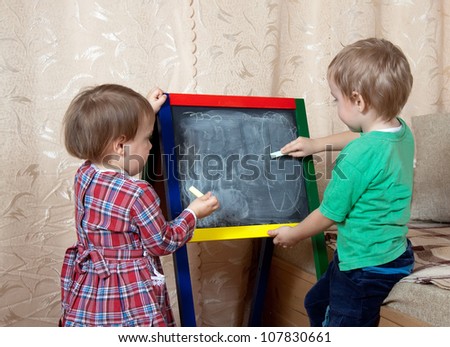 children draws on the blackboard with chalk at home