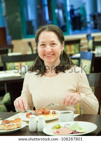 Mature woman having breakfast in hotel restaurant