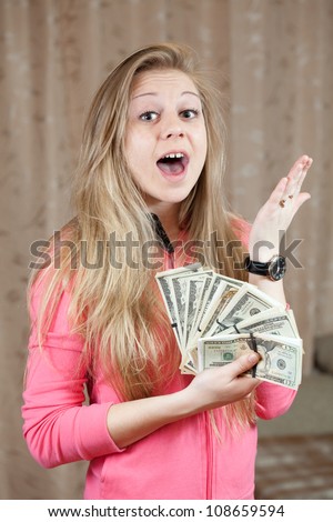 Happy young woman shows bundles of US dollars  in home