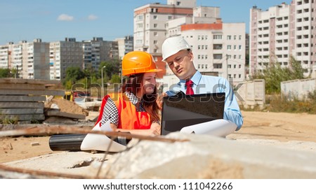 Two architects wearing protective helmet standing in front of building site