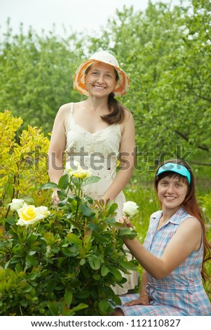 Happy women in yard gardening with roses plant