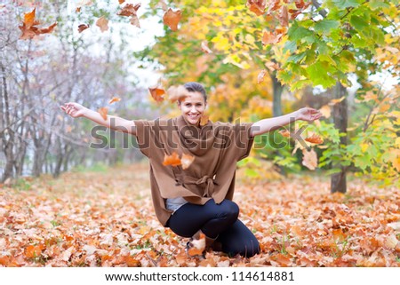 Woman throws autumn leaves in the park