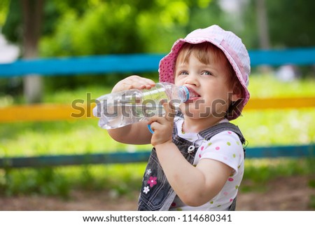 2 years child drinks from plastic bottle in park