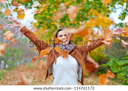 Happy woman throws autumn leaves in the park
