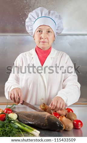 Cook woman  cooking fish  in kitchen