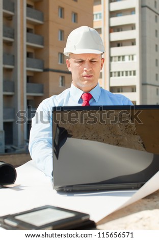 Portrait of white-collar worker wearing protective helmet works on the building site