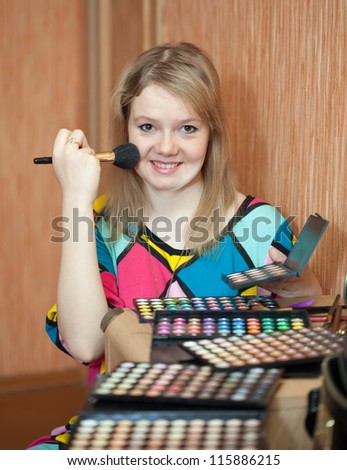 Girl putting facial powder on her face with a brush