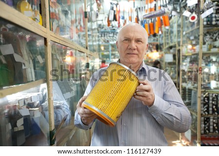 mature man holds  automotive  air filter in  auto parts store