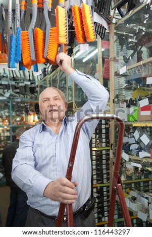 mature man chooses  automotive broom  in  auto parts store