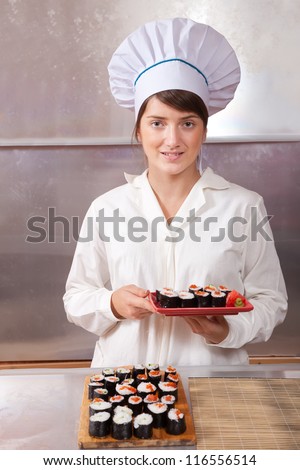 Cook woman with cooked  sushi rolls in kitchen