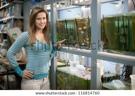 Woman chooses  fish in aquariums at pet-shop