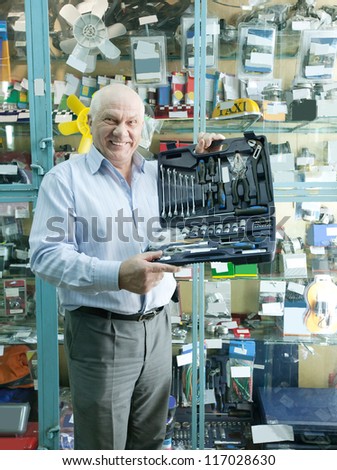 mature man holds  automotive  correction tool set in  auto parts store