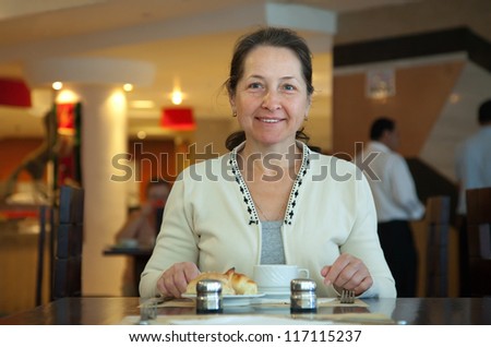Mature woman having breakfast in hotel restaurant