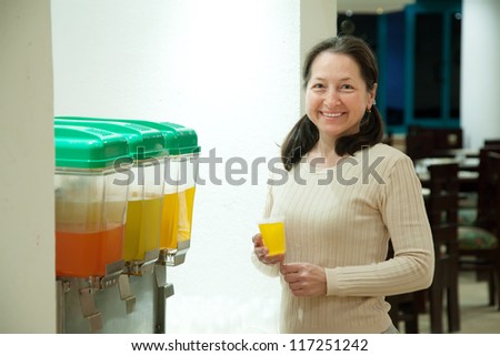Woman pours near juice container at restaurant