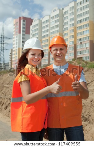 two happy builders in hardhat works on the building site