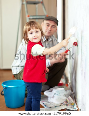 child  with father paints wall  at home