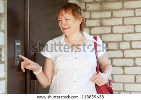 Mature woman pushing button of house intercom