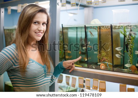 Woman near aquariums with fishes in pet-shop