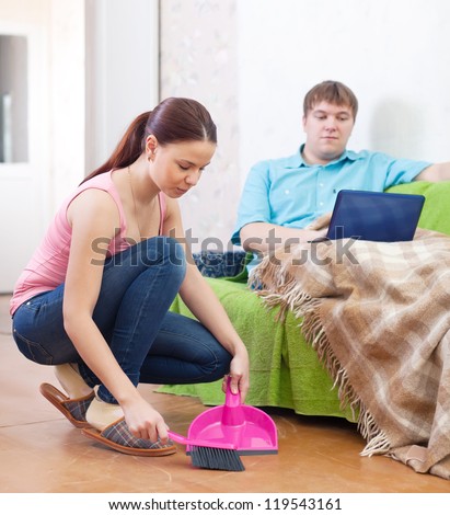Clean up woman, while her husband lying on the sofa