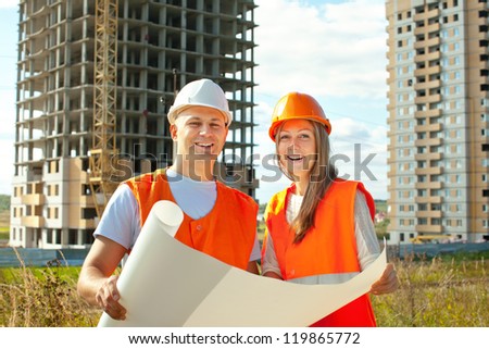 two workers wearing protective helmet works on the building site
