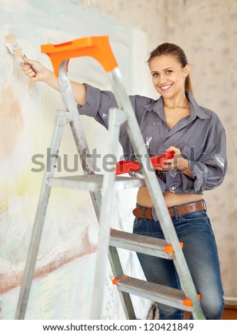 Happy woman paints wall with brush