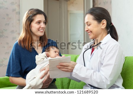 friendly mature pediatrician doctor talks with mother of newborn baby. Focus of mother