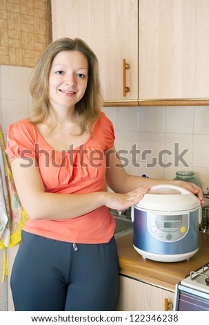 Young woman with electric slow cooker in her kitchen at home