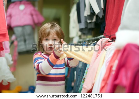 2 years baby girl looking at wear in clothes shop