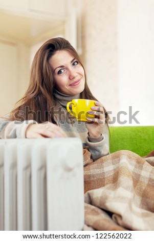 smiling woman  with yellow cup near oil heater