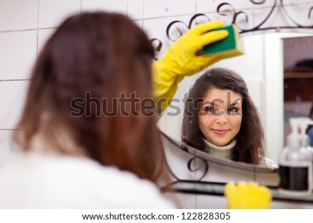 Pretty woman cleans  mirror in bathroom at home