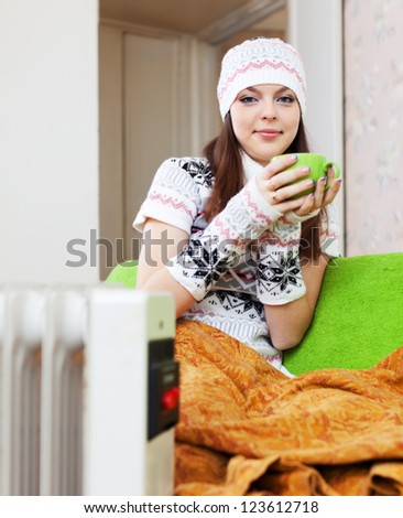 woman relaxing with cup near heater at home in winter