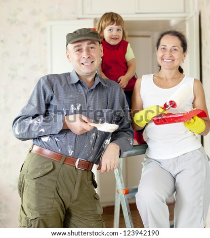 Happy family of three makes makes repairs in the apartment together