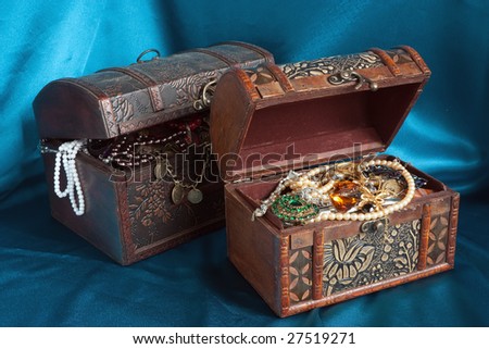 Two wooden treasure chest with valuables on blue textile