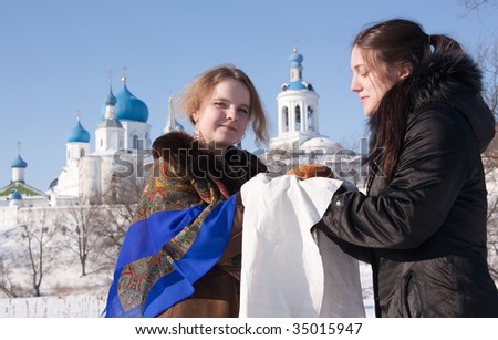 A girl in russian traditional kerchief  gives loaf a tourist