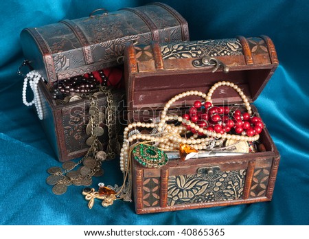 Two wooden treasure chests with valuables on blue textile