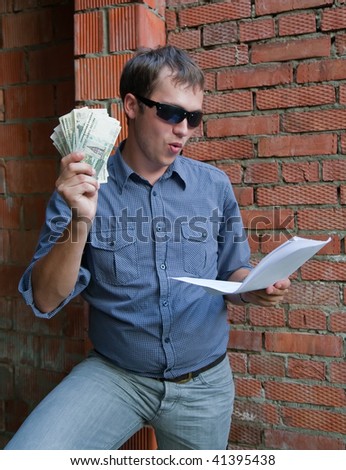 Happy worker with documents and money  against  the brick wall