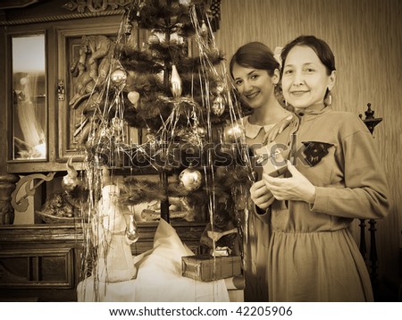 Retro photo of  daughter with mother near Christmas tree at home
