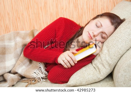 woman sleeps on sofa in livingroom with book