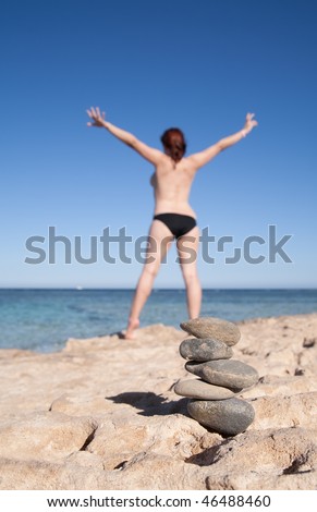 Balanced stones and  girl doing yoga against sea, Focus on stones