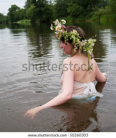 Girl dressed in pareo and flower wreath  in river