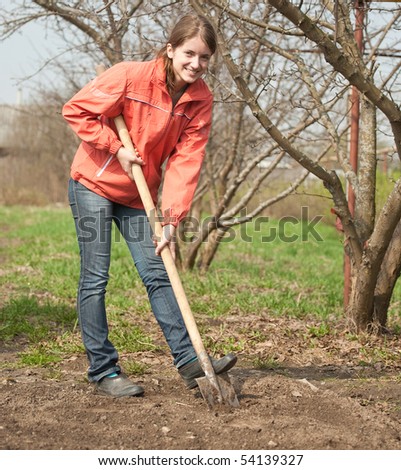 young woman working with shovel in orchard